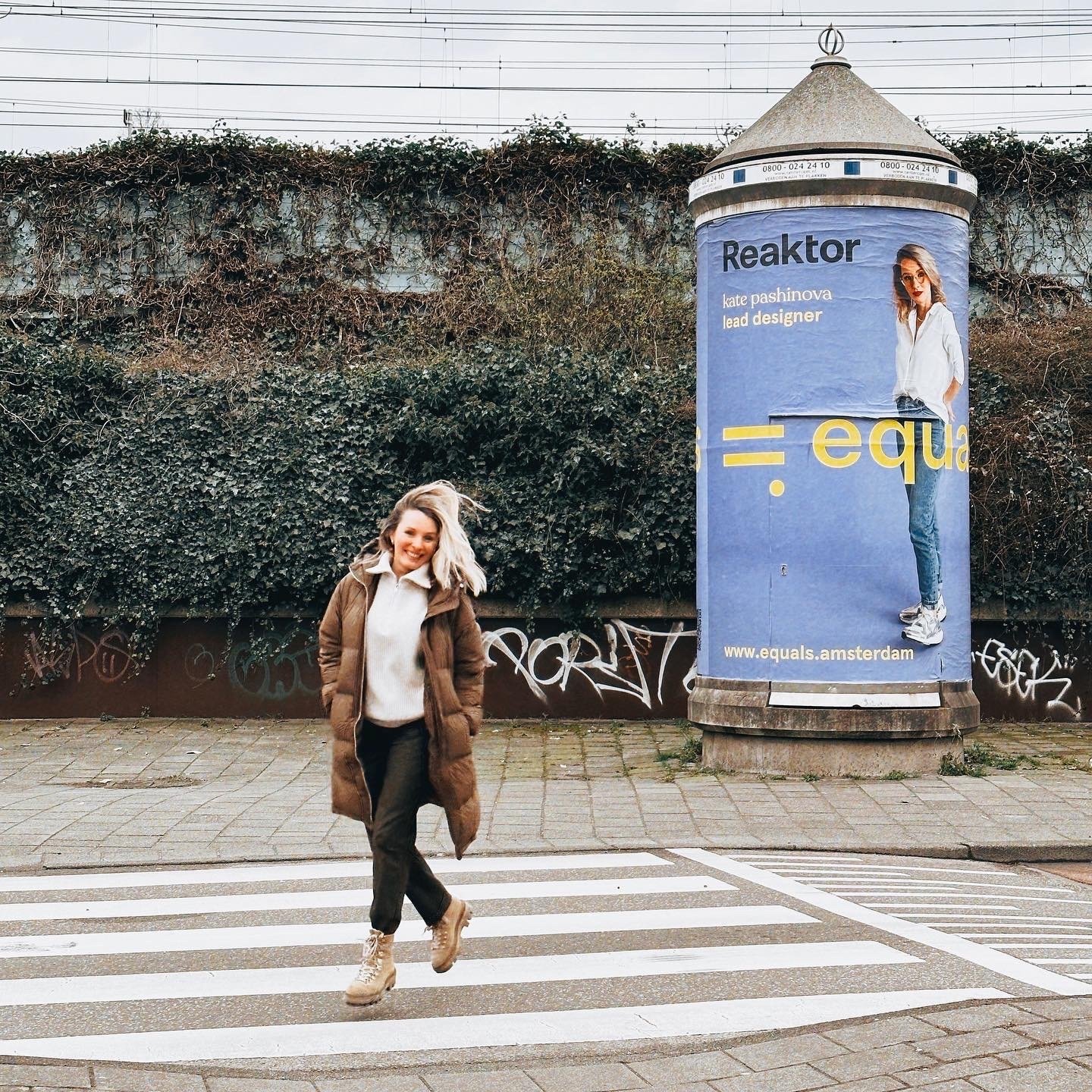 A woman walking on a street, an Equals campaign advertisement of her behind her