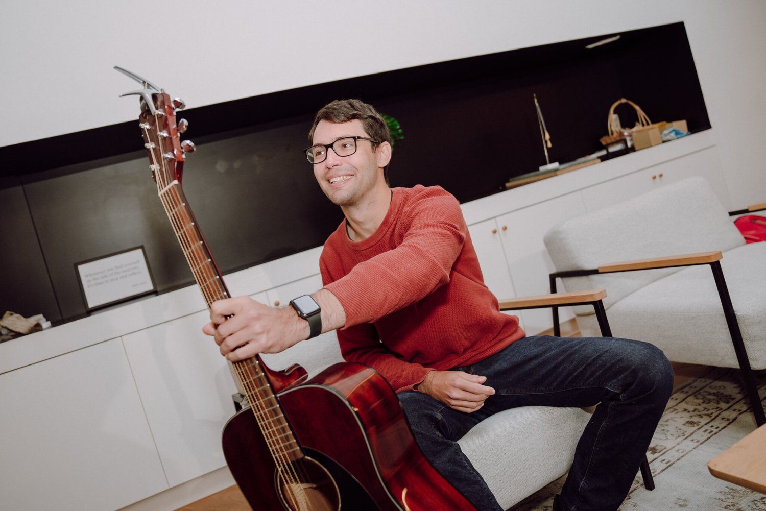 A reaktorian at Reaktor Amsterdam office sitting on a couch holding a guitar